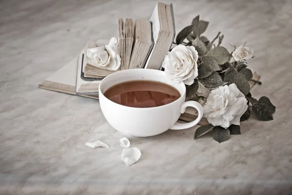 Cup of tea with white flowers and books