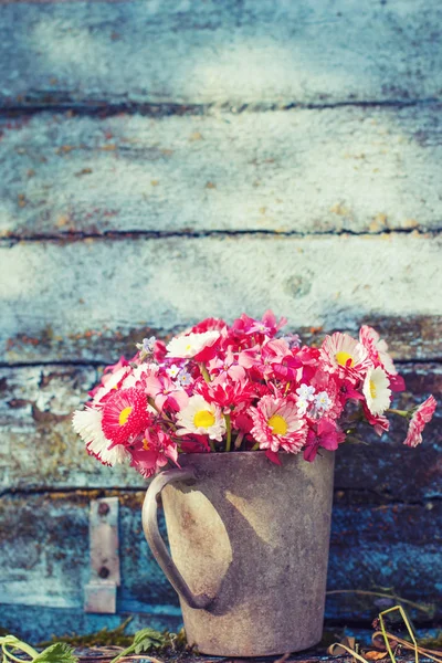 ぼろぼろの木製の背景に金属製の鍋にピンクと白の野生の花の花束 — ストック写真