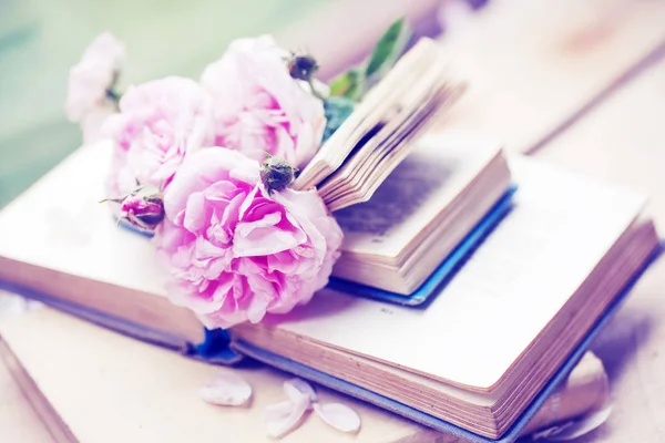 closeup view of peonies flowers on books over wooden background