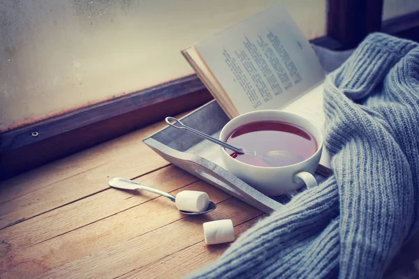 cup of hot tea and book on wooden surface