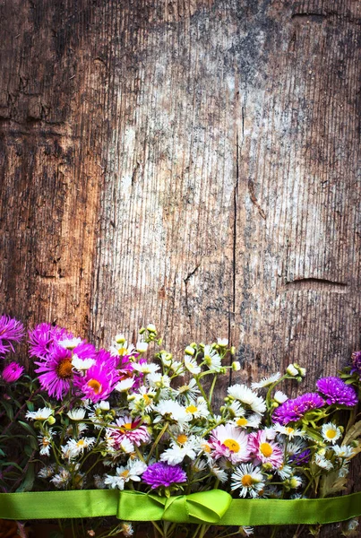 茶色の木製の背景にカラフルな野生の花 — ストック写真