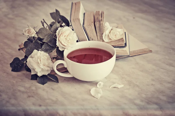 Cup of tea with white flowers and books