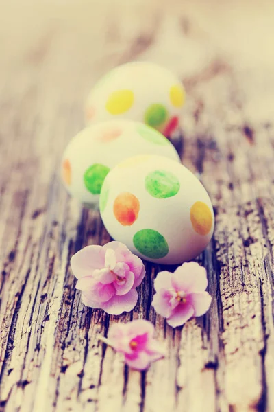 Colorful painted eggs with pink flowers on wooden background