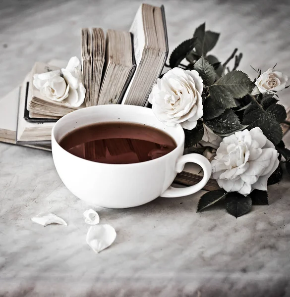 Cup of tea with white flowers and books