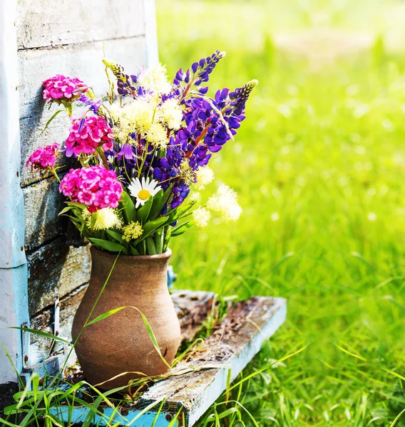 五颜六色的新鲜野花在花瓶对木墙花束 — 图库照片