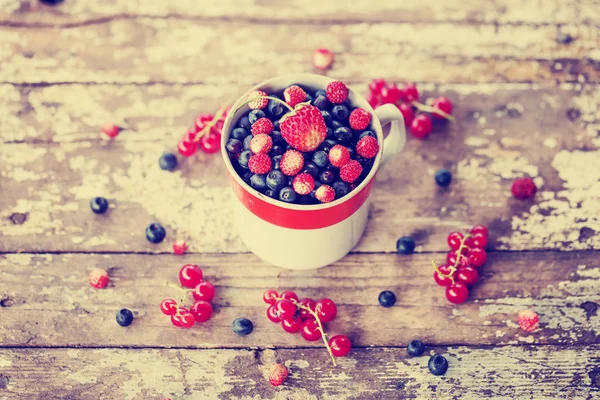 Myrtilles Fraîches Dans Une Tasse Avec Fraise Sur Une Surface Image En Vente