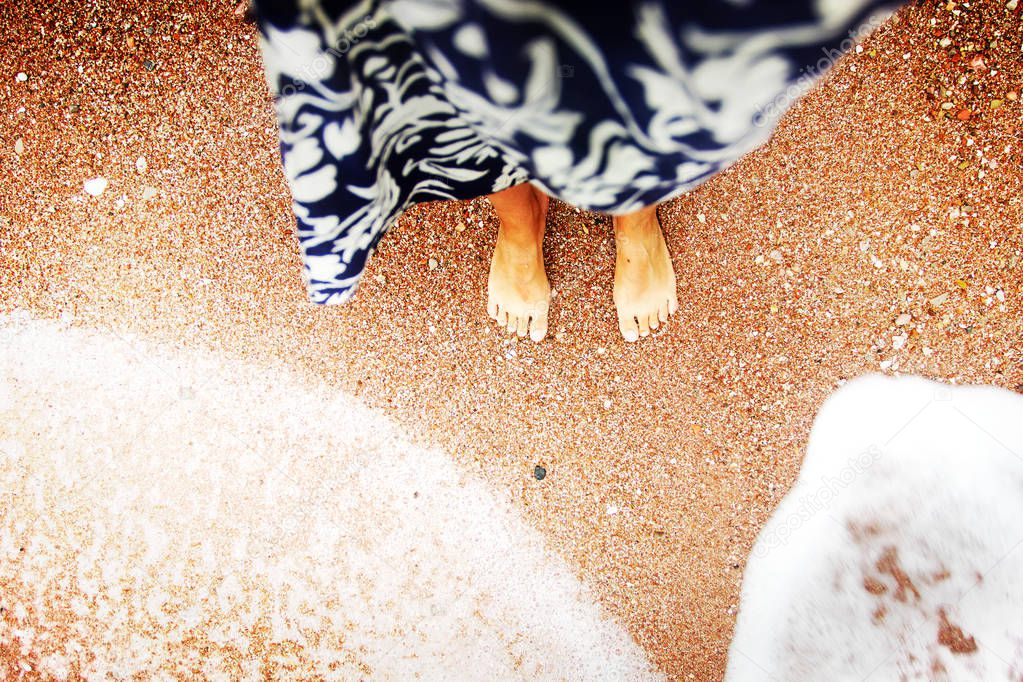 low angle view of female bare feet on sand at beach