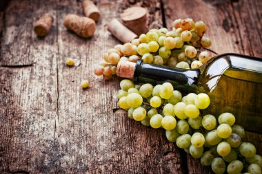 Bir şişe şarap, üzüm ve ahşap masa tarihinde mantarlar