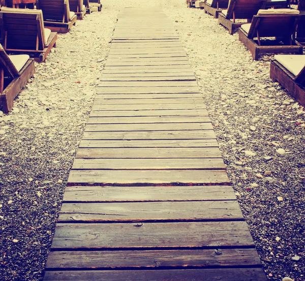 wooden path on beach among deck chairs in vintage colors