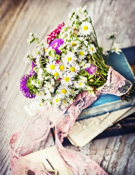 bouquet of wild flowers on shabby wooden table with vintage books
