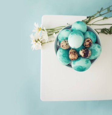 Pastel ve papatya çiçekler kase ile renkli Paskalya yumurtaları