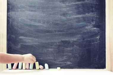 Pastel renkli tebeşir parçaları yazı tahtası, okul kavramı alarak çocuk el