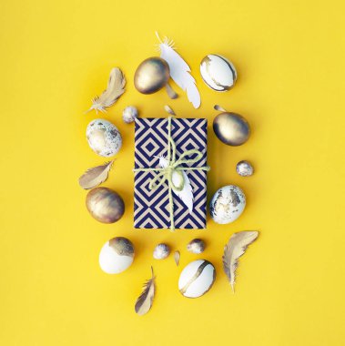 Dekoratif renkli Paskalya yumurtaları, sarılmış hediye ve Sarı zemin üzerine tüy şenlikli Paskalya düz yatırın