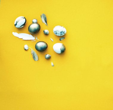 Dekoratif renkli Paskalya yumurtaları ve Sarı zemin üzerine tüy şenlikli Paskalya düz yatırın