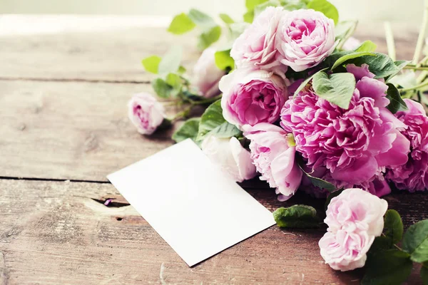 Beautiful pink bouquet and greeting card on table, natural spring background