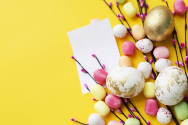 Sarı arka plan üzerinde boş kart ile renkli Paskalya yumurta süslemeli el yapımı willow dal