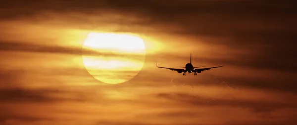 Beautiful sunset with airplane landing — Stock Photo, Image
