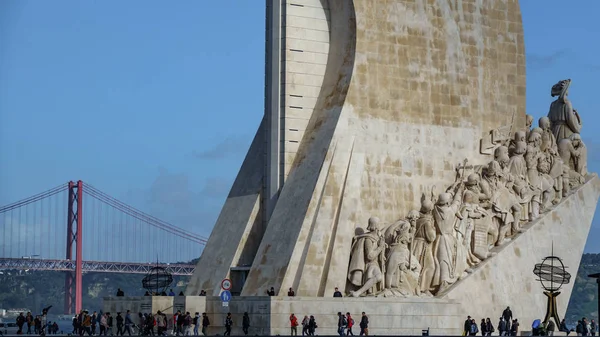 LISBOA, PORTUGAL - 4 DE ABRIL DE 2018: Turistas no identificados visitan Monumento aos Descobrimentos con el puente 25 de abril en el fondo en Lisboa, Portugal — Foto de Stock