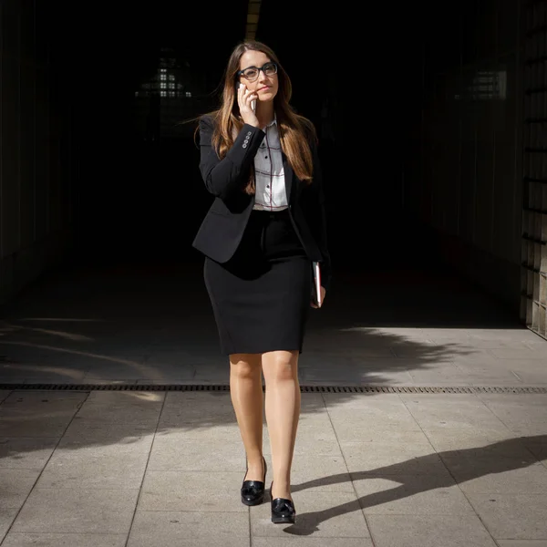 Woman walks out of the dark talking by phone — Stock Photo, Image