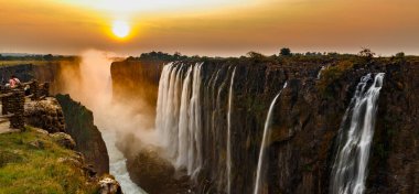 Turuncu güneş ve turistler ile Victoria falls günbatımı panorama