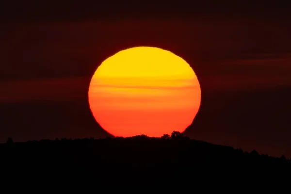 Sunrise over mountain peak with huge orange sun on top — Stock Photo, Image