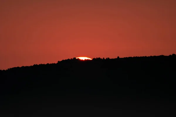Sol saliendo detrás de la montaña oscura un poco — Foto de Stock