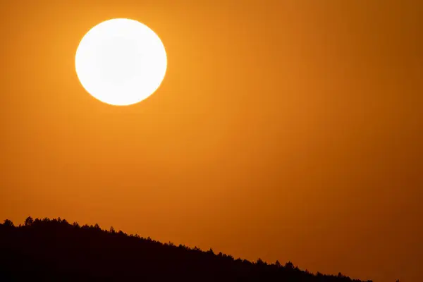 Big sun circle at dusk over mountain with orange sky — Stock Photo, Image