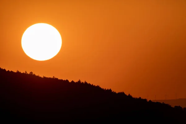 Grote zon cirkel in de schemering over bergen met oranje hemel — Stockfoto