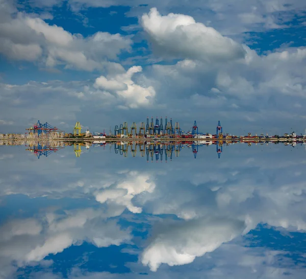 Облака над коммерческими портовыми кранами с отражением — стоковое фото