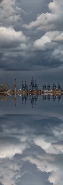 Storm over commercial symmetric port cranes reflected — Stock Photo, Image