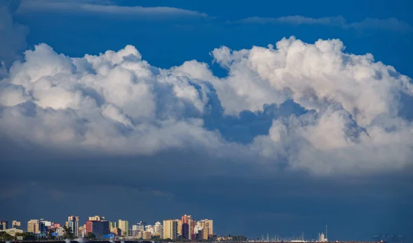 Rascacielos cerca del mar con nubes tormentosas como sombrero —  Fotos de Stock