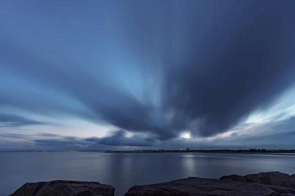 Langzeitbelichtung bei Sonnenuntergang von Wellenbrecher mit Meer und Küstenstadt — Stockfoto