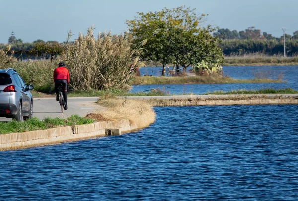 Cyklist och bil i vägen nära dammen — Stockfoto