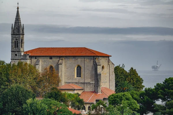 Iglesia de Mundaka con plataforma oceánica de gas en el fondo —  Fotos de Stock