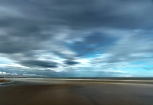 Dramatische stormachtige wolken boven strand met gebouwen van kust en zee — Stockfoto
