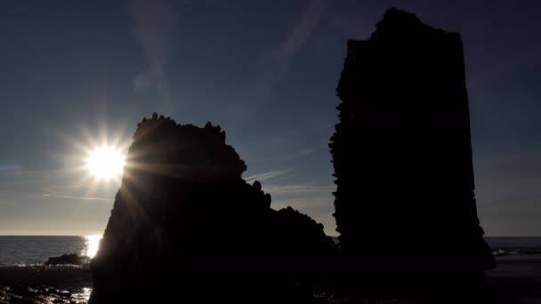 Contre-jour près de l'océan avec tour délabrée et brise-vagues — Video