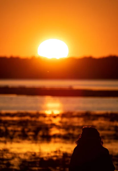 Ženská silueta pozorovat východ slunce nad jezerem — Stock fotografie