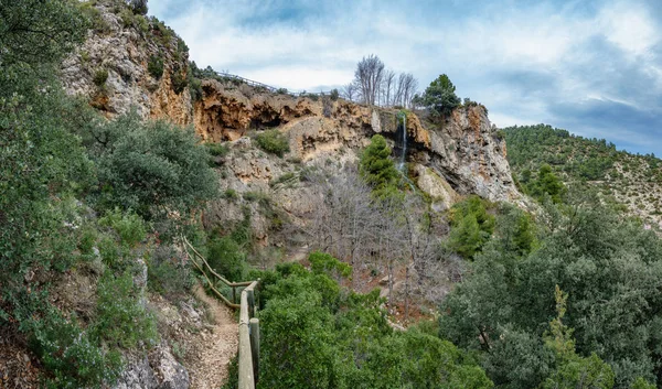 Track to caves and waterfall against cloudy sky — Stock Photo, Image