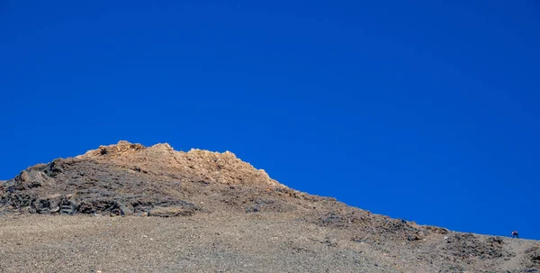 Бегун поднимается на трудный склон Тейде вулкан против голубого неба — стоковое фото