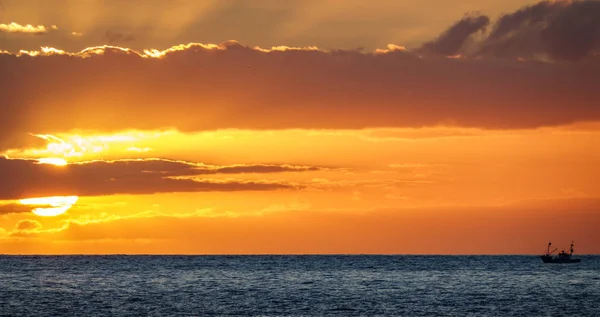 Visserij boot saling naar de zon in de horizon bij zonsondergang — Stockfoto