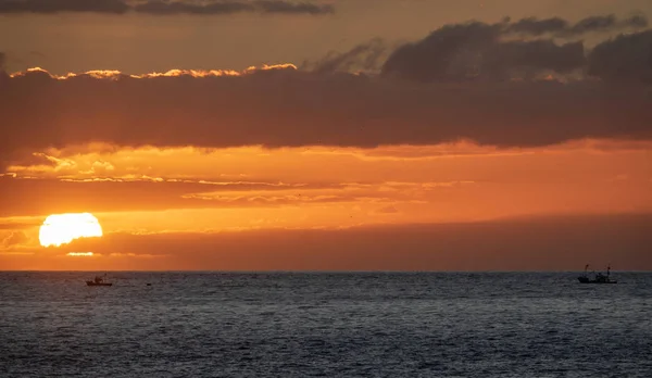 Sunset over the ocean with two small fishing boats — Stock Photo, Image