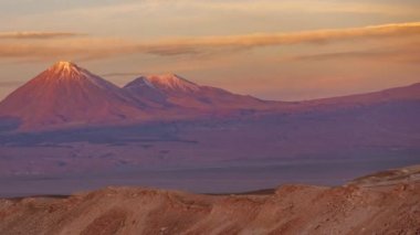 Pembe gökyüzü ile gün batımında dolunay yükselişi ile Licancabur yanardağ zaman atlamalı