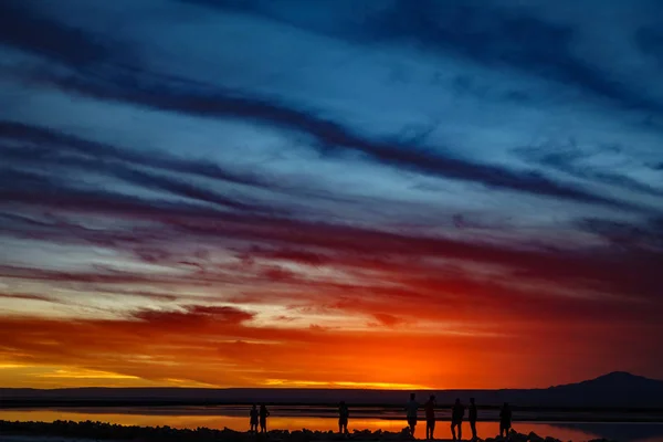 Tramonto in salar con cielo arancione e sagome turistiche — Foto Stock