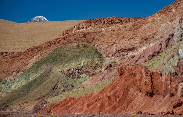 Valle del arco iris con múltiples colores y pico del volcán Licancabur — Foto de Stock