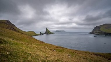 Arka planda Mykines ile Tindholmur önünde Drangarnir kapısı WDE açı görünümü Timelapse