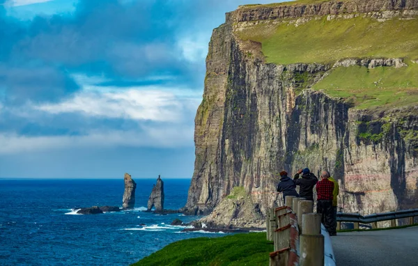 Neznámi turisté pozorují obra a Wiche na severním pobřeží Eysturoye na Faerských ostrovech.. — Stock fotografie