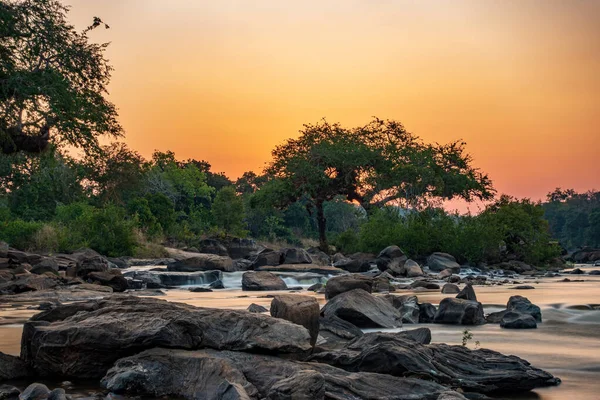 Tramonto ultra lunga esposizione nel fiume Malawi con alberi e rocce — Foto Stock