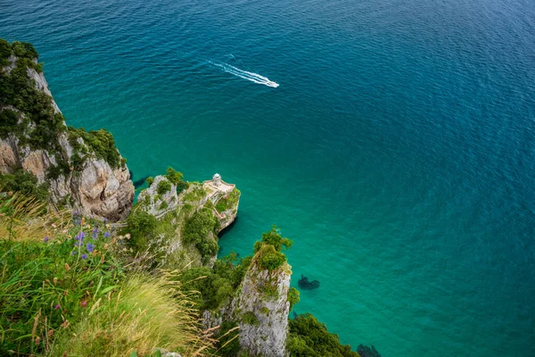 Phare sur la côte escarpée avec bateau et mer vert vif — Photo