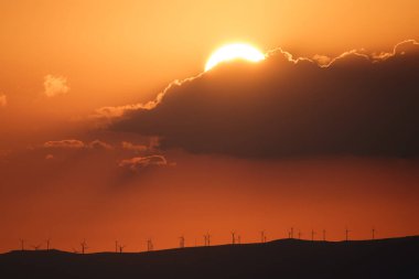 Günbatımı modern yel değirmenleriyle dağların üzerinde