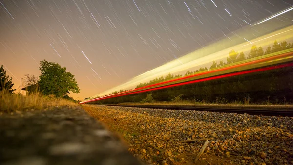 Long exposure night star trails with blurred train, fast speed — Stock Photo, Image